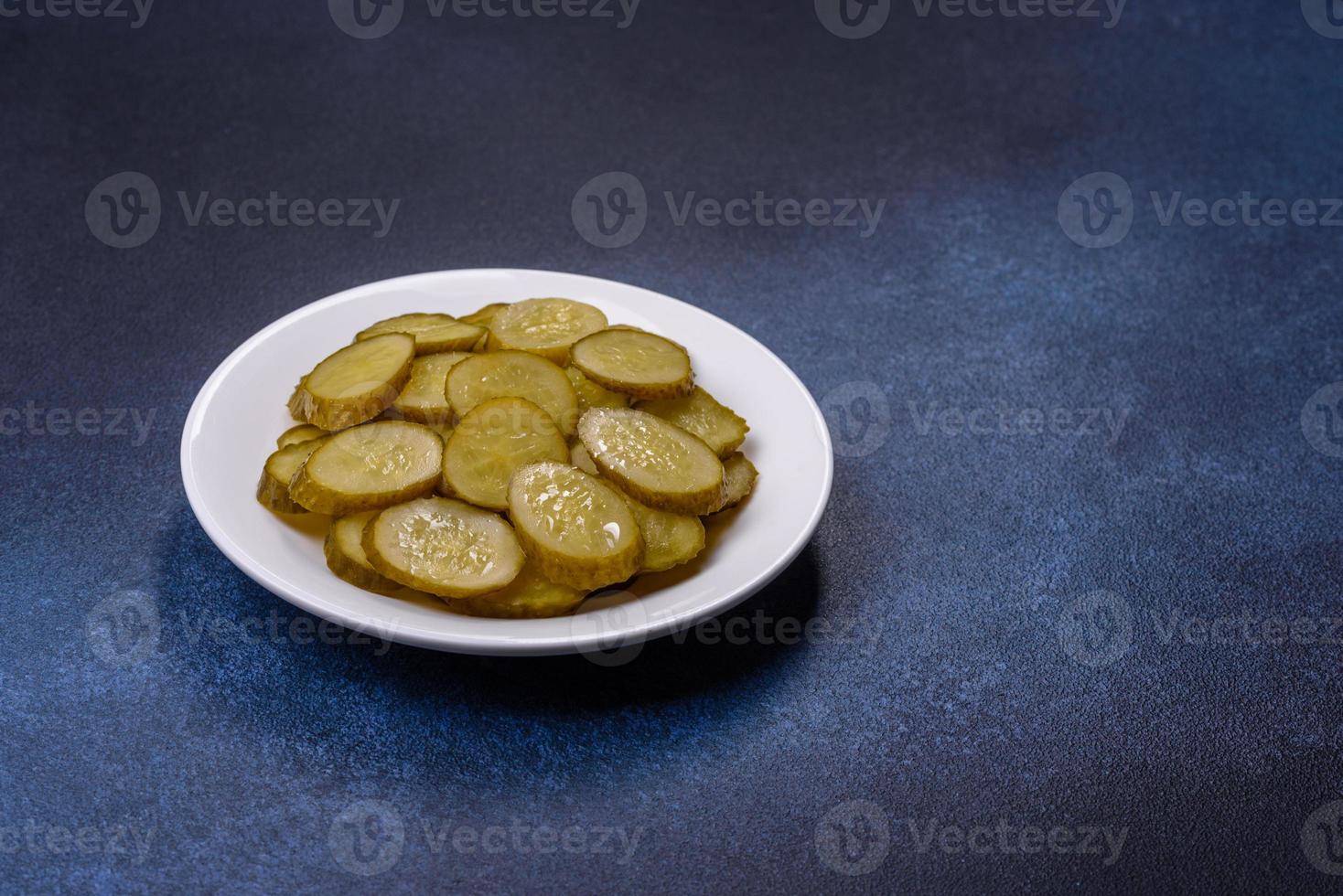 Delicious salted, canned cucumbers cut into slices on a white ceramic plate photo