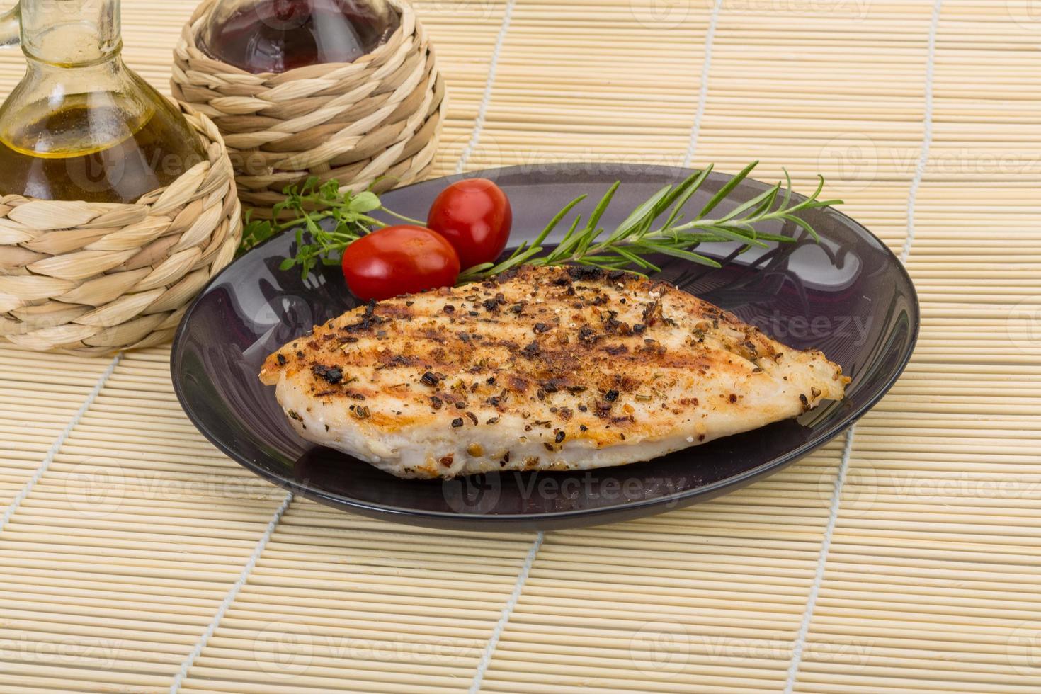 Grilled chichen breast on the plate and wooden background photo