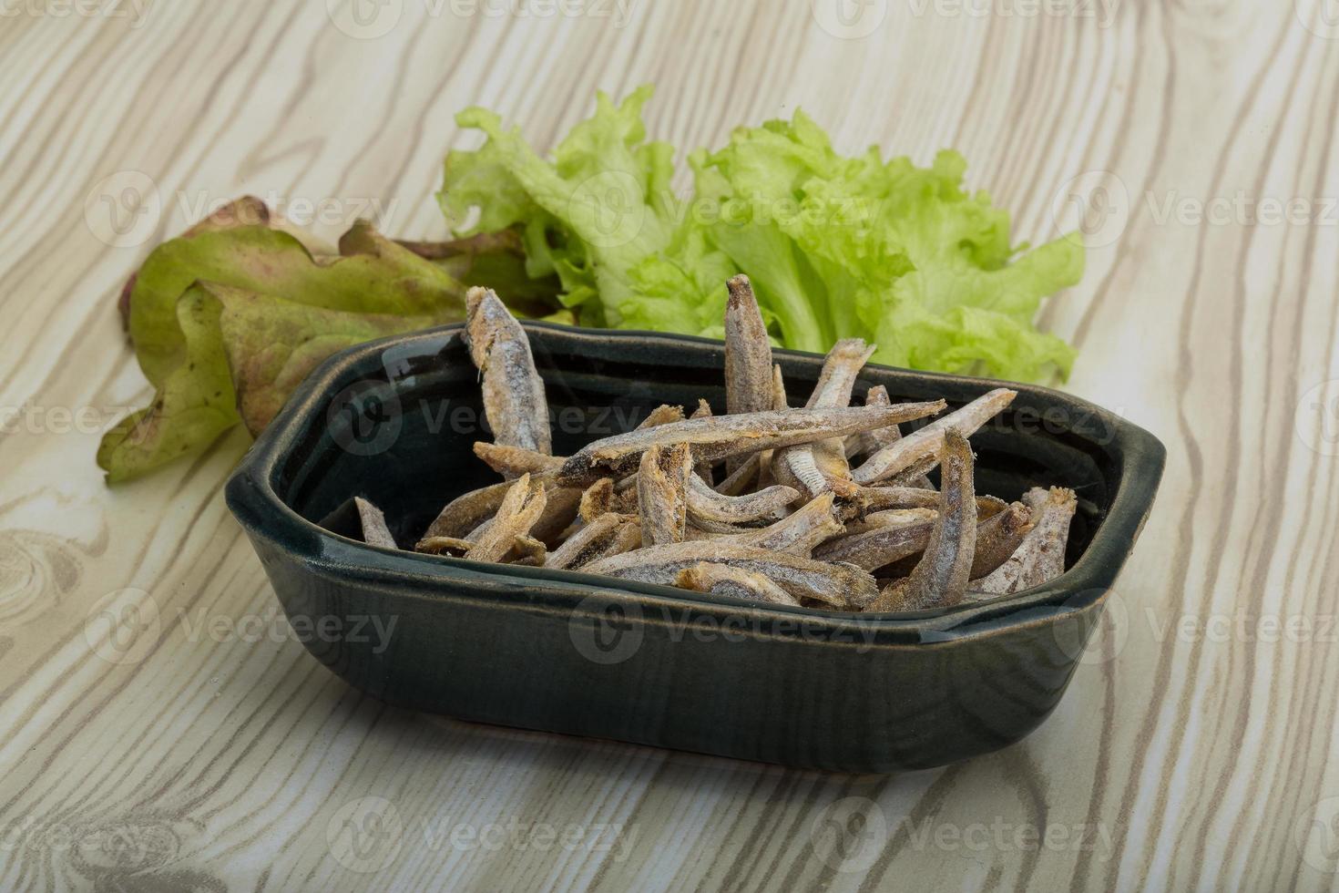 Dries anchovy in a bowl on wooden background photo