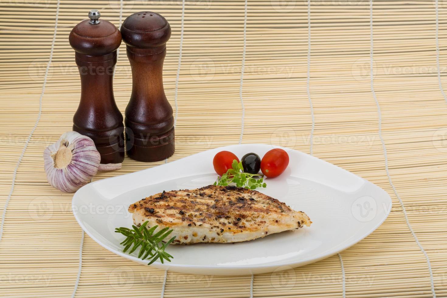 Grilled chichen breast on the plate and wooden background photo