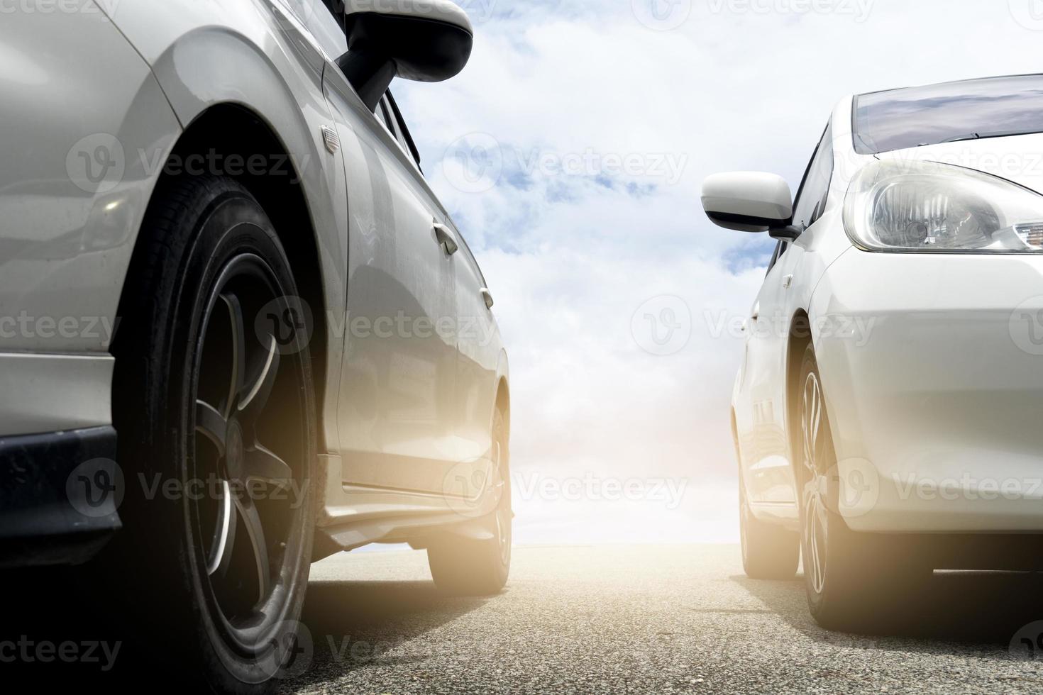 Abstract of beside of two cars on the asphalt road. Park the car outdoors next to each other. Or parpare for the race. with background outdoor of blue sky and white clouds with sunlight. photo