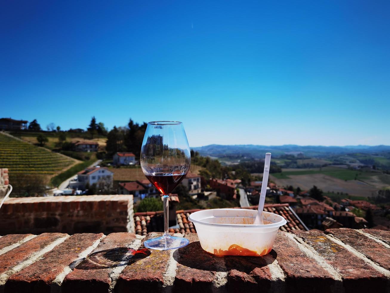 glass of wine and plate of ravioli with a view of the Piedmontese Langhe of Monforte d'Alba photo