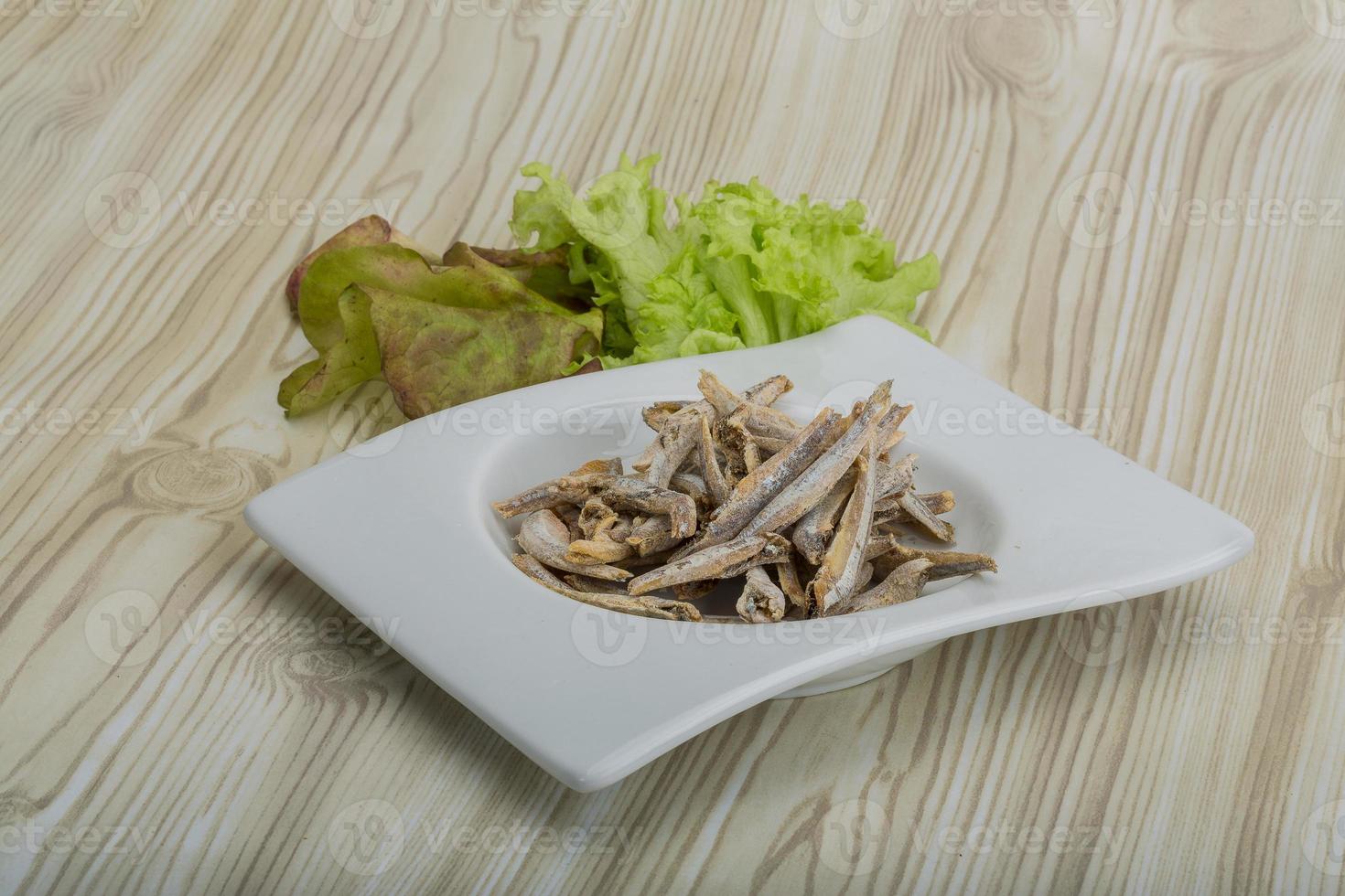 Dries anchovy in a bowl on wooden background photo