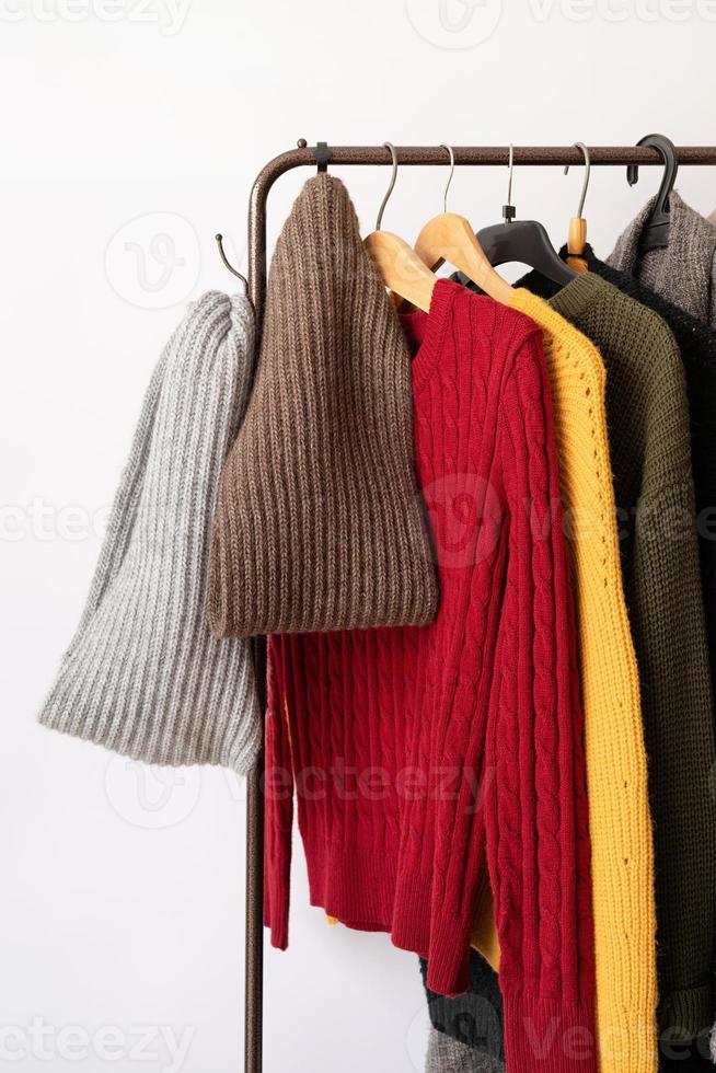 Row of different colorful Knitted sweaters hang on hangers, white background photo