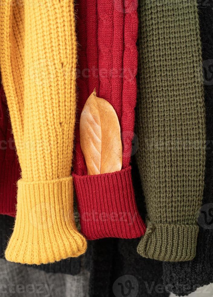 Row of different colorful Knitted sweaters hang on hangers, white background photo