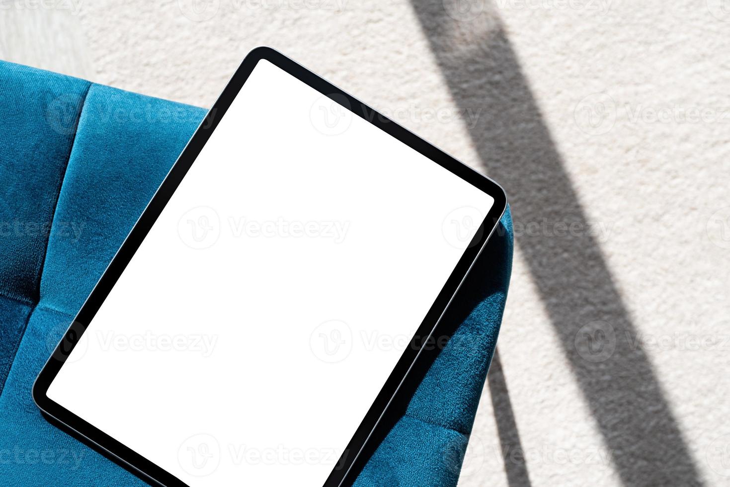 Digital tablet computer with isolated screen on blue chair. At home interior. photo