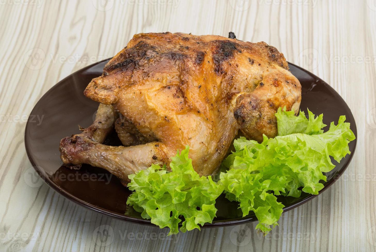 Roasted chicken on the plate and wooden background photo