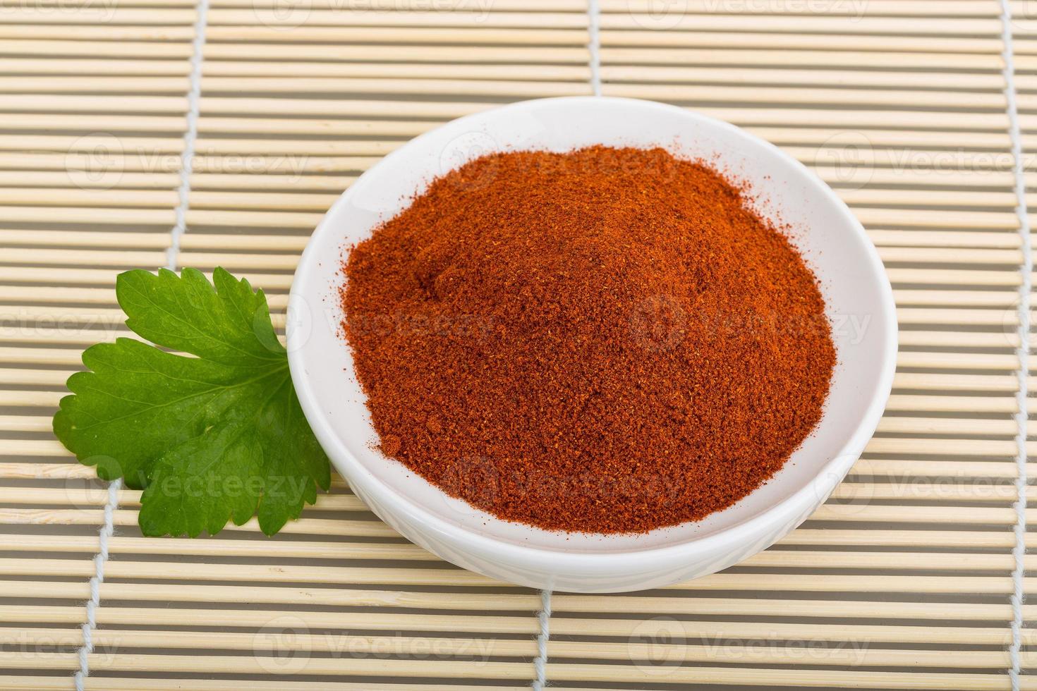 Paprika powder Paprika powder on the plate and wooden background photo