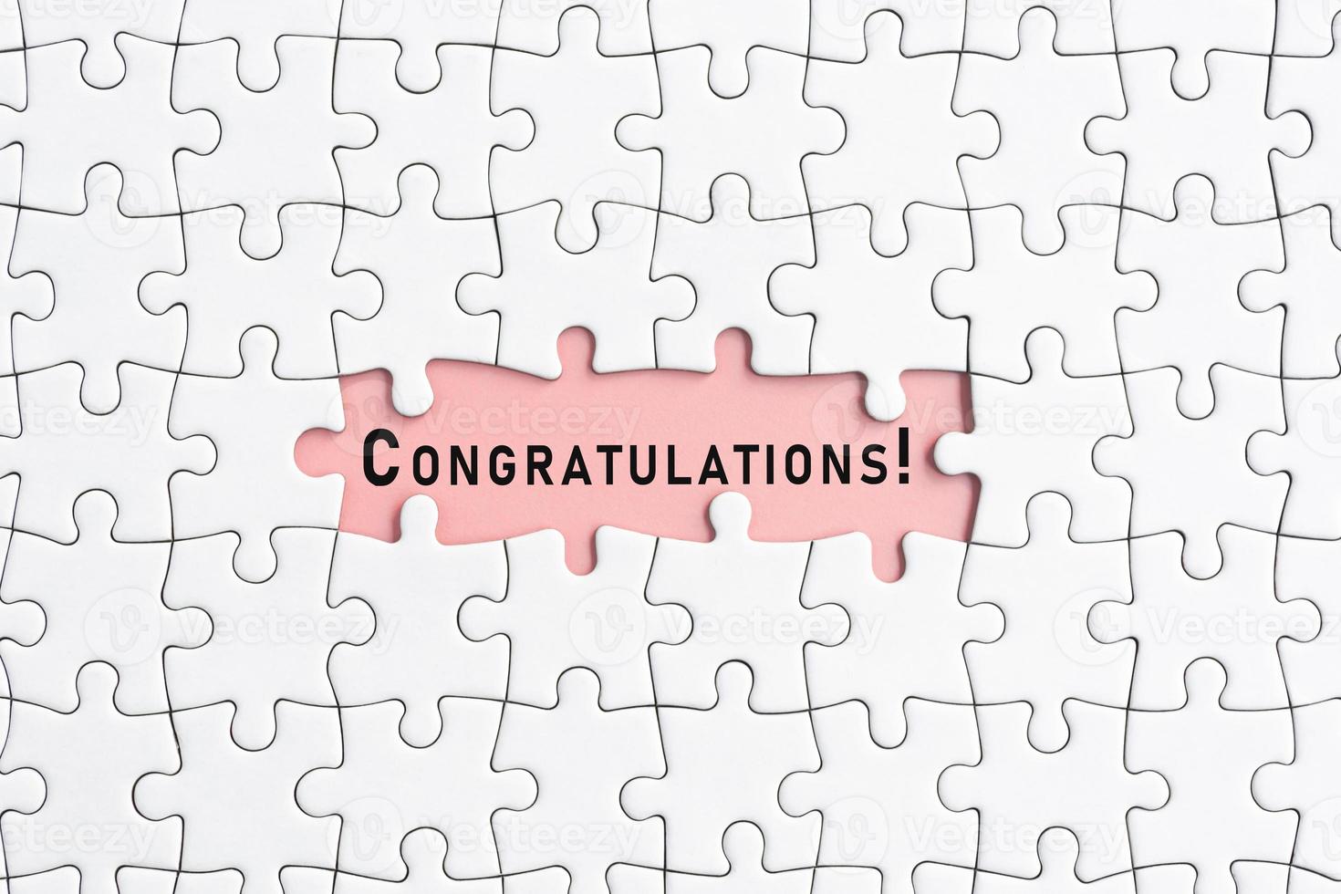 White jigsaw puzzle with congratulations word over pink background. photo