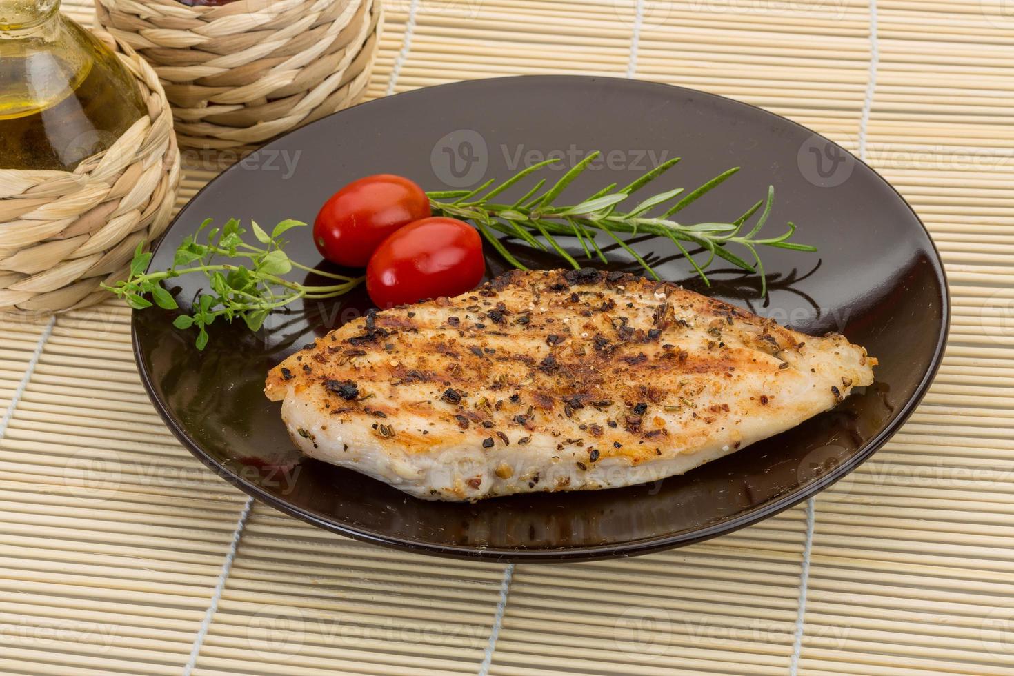 pechuga de pollo a la parrilla en el plato y fondo de madera foto