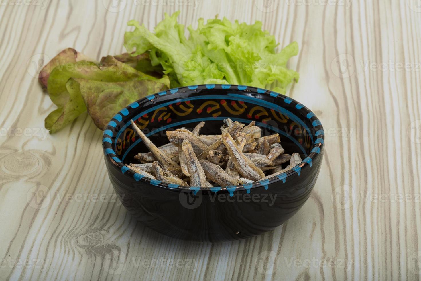 Dries anchovy in a bowl on wooden background photo