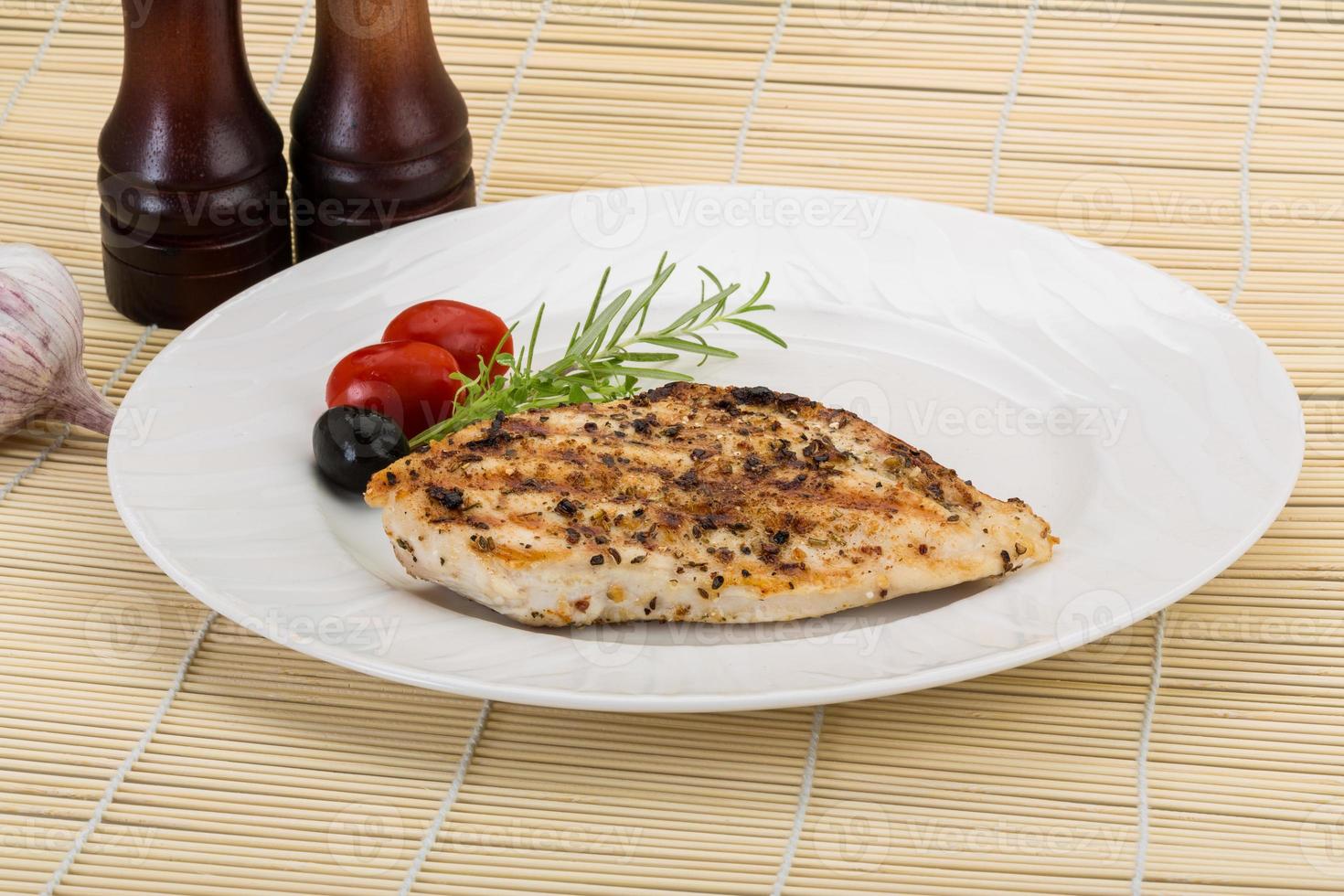 Grilled chichen breast on the plate and wooden background photo