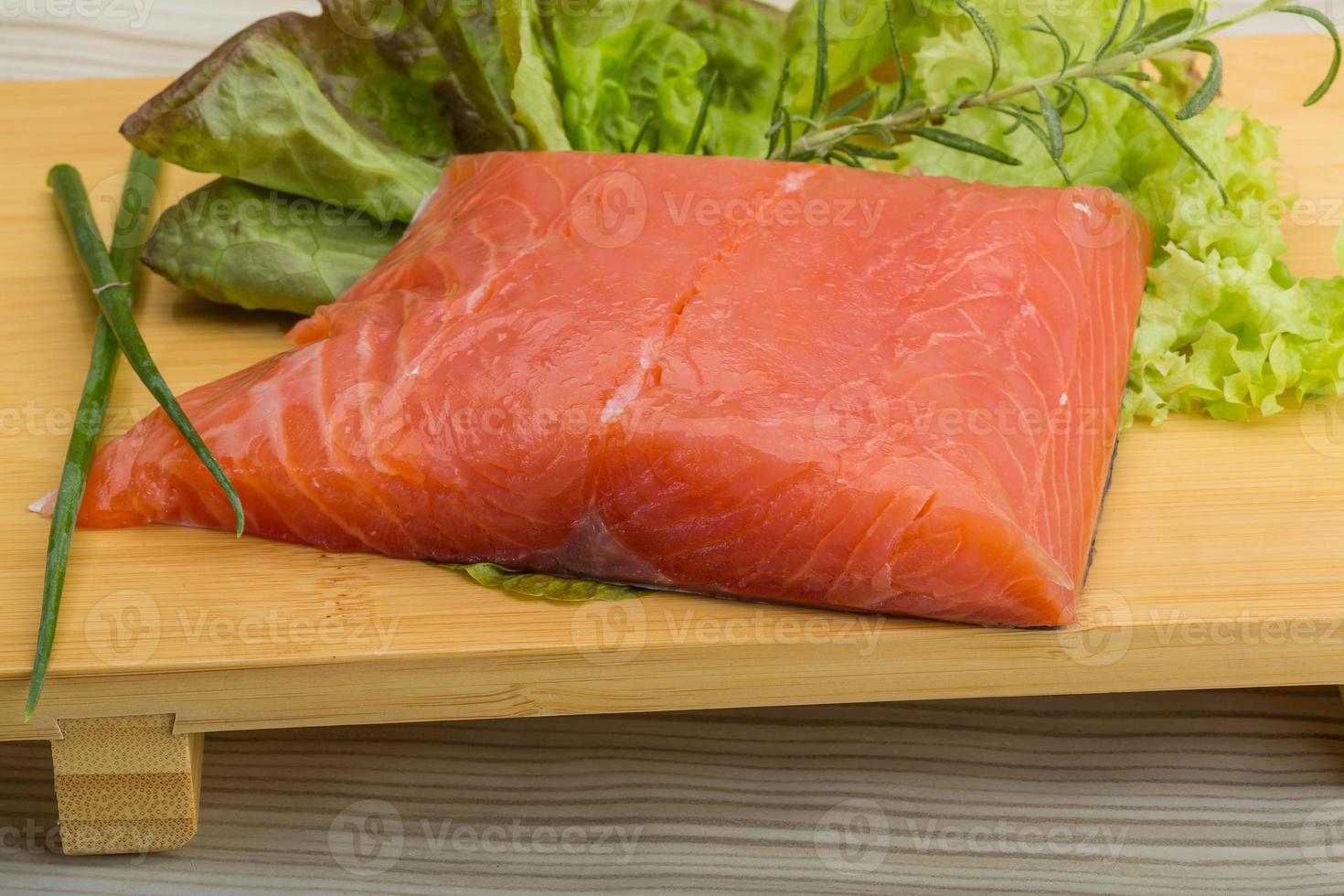 Salmon fillet on wooden board and wooden background photo
