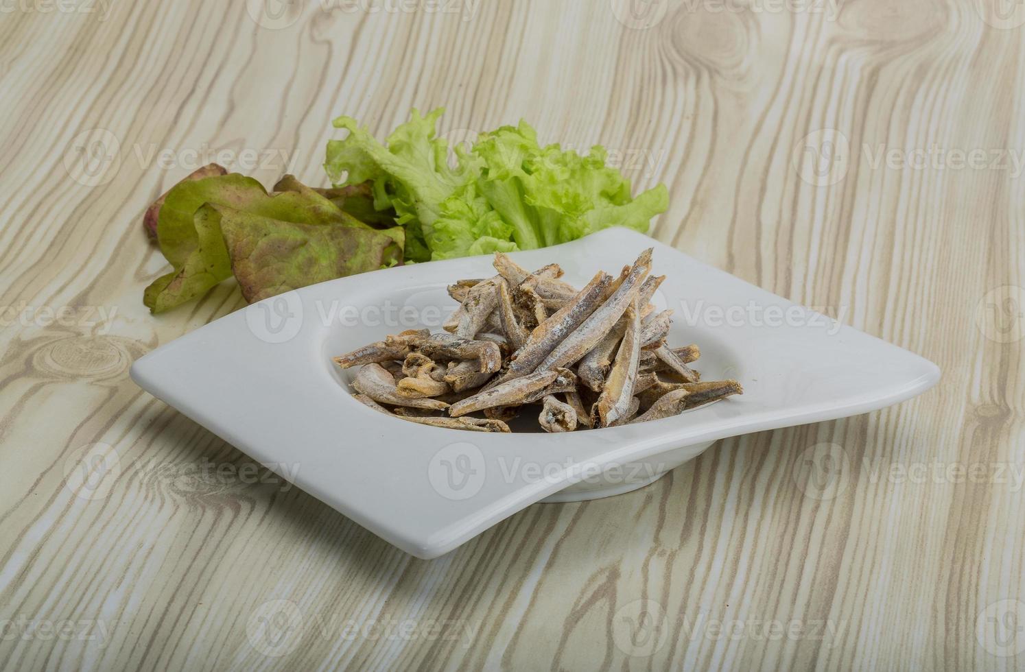 Dries anchovy in a bowl on wooden background photo