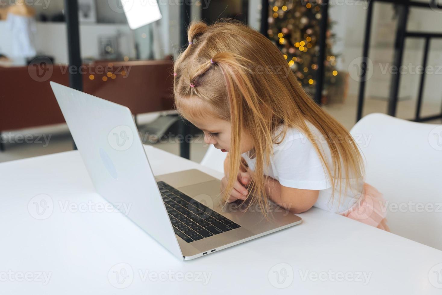 Little girl using tablet computer sitting at table photo
