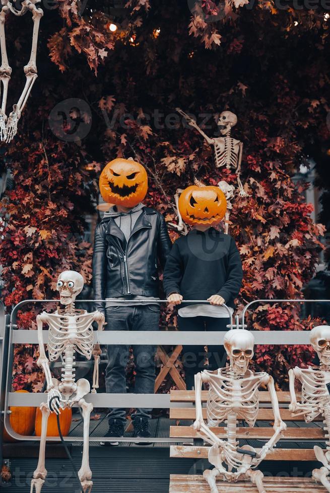 A guy and a girl with a pumpkin heads posing on the street photo