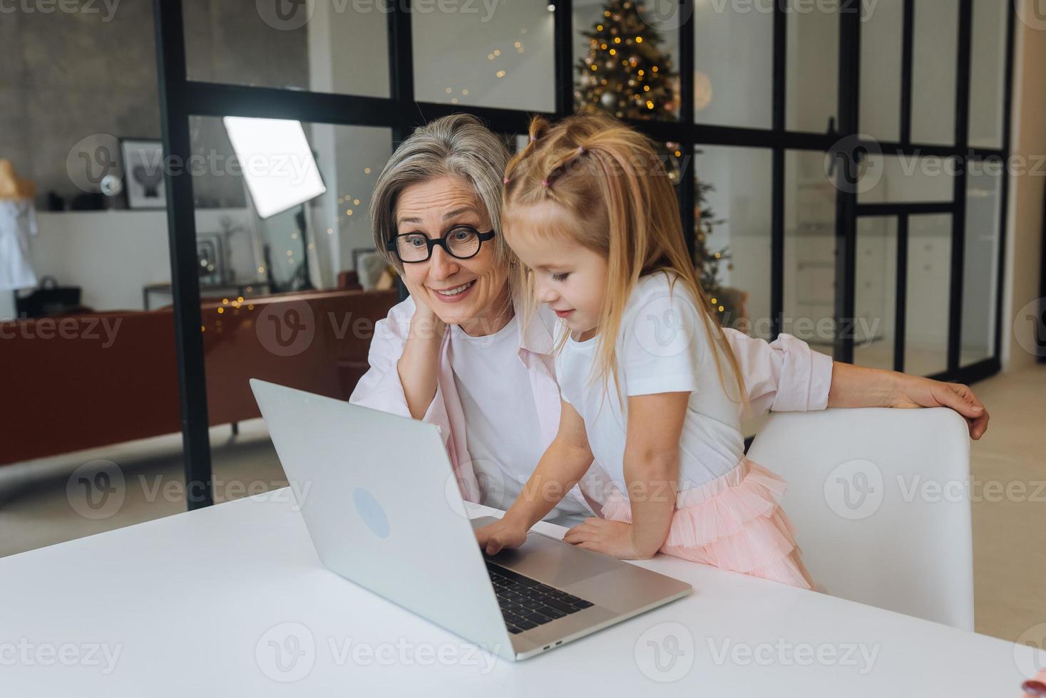 niño y abuela mirando la cámara con laptop foto