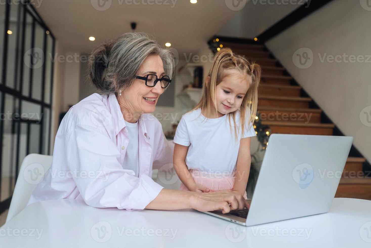 niño y abuela mirando la cámara con laptop foto