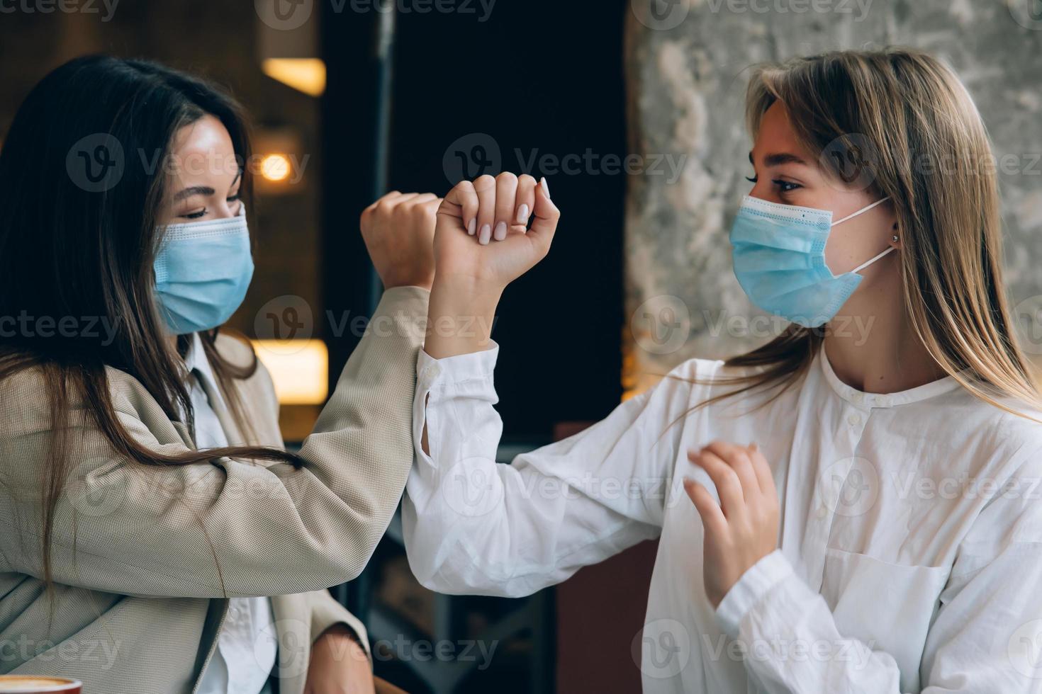 Co-workers in protective masks giving high five with elbows. photo