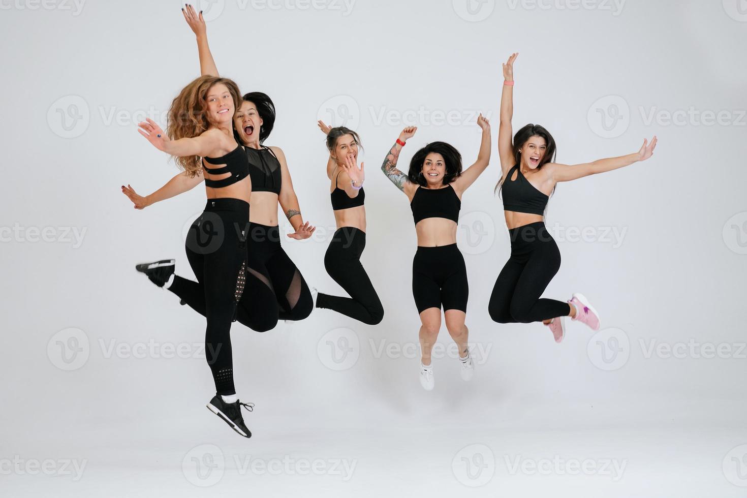 diverse models jump up, enjoying time together, look at camera photo