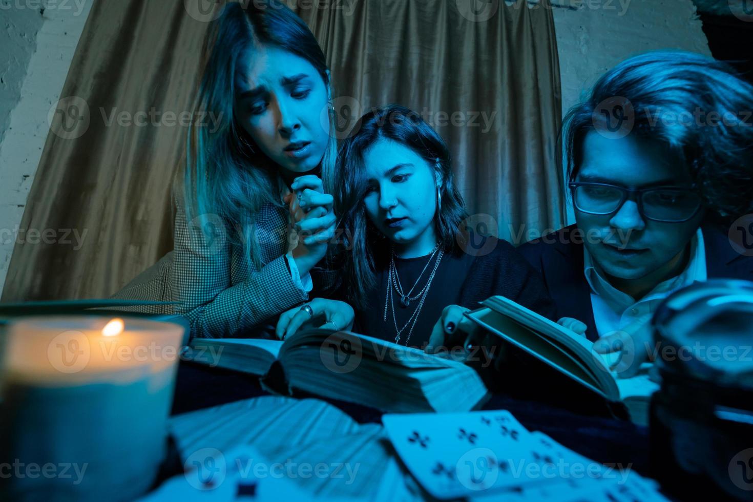 Two women and a guy are reading a mysterious books, close view photo