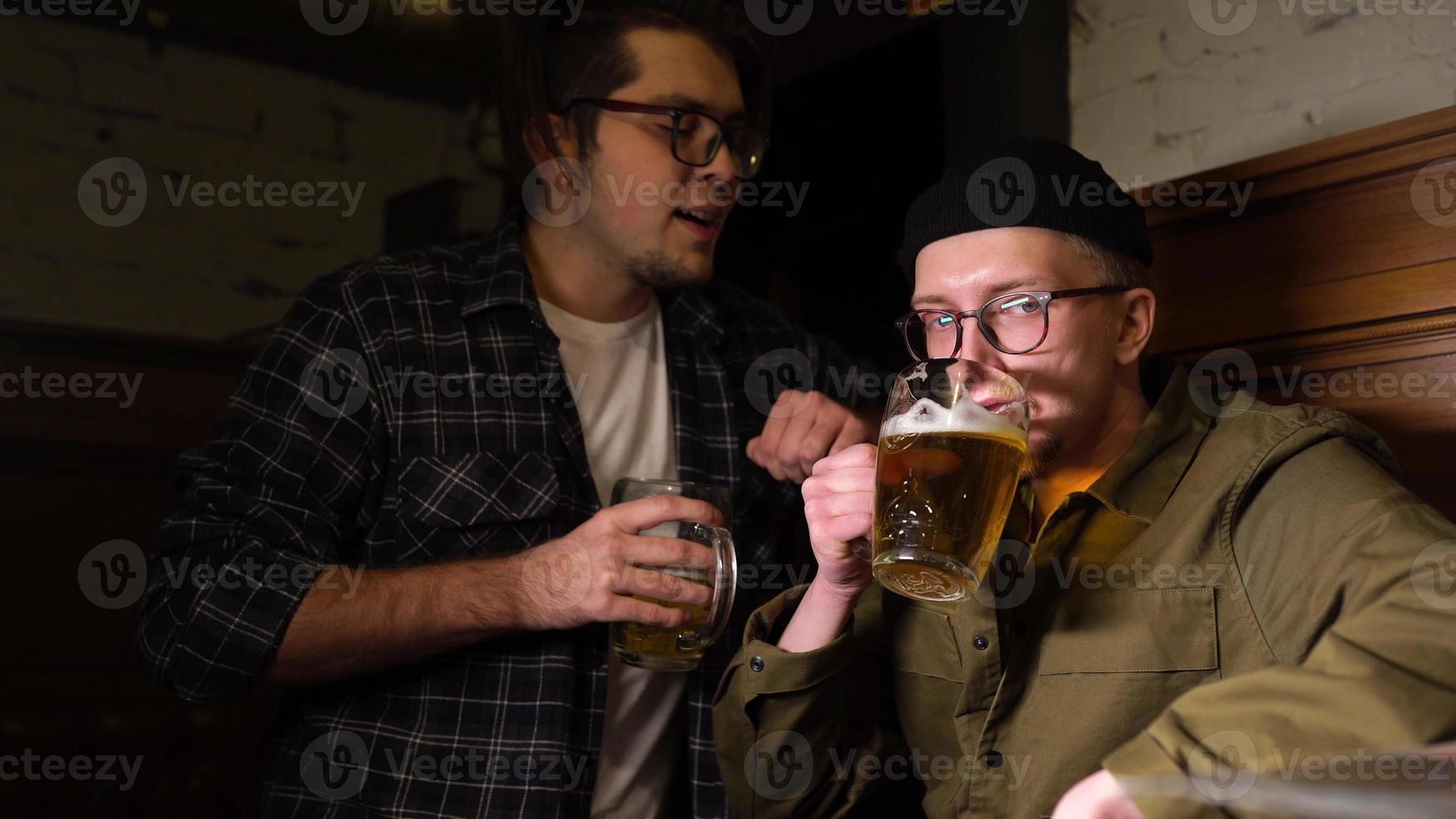 Young friends having fun together drinking beer and clinking glasses in a pub. photo