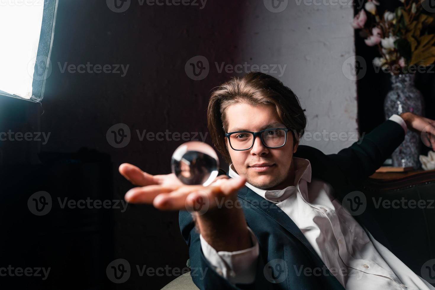 Young man holding a clear transparent crystal glass ball in their hand photo