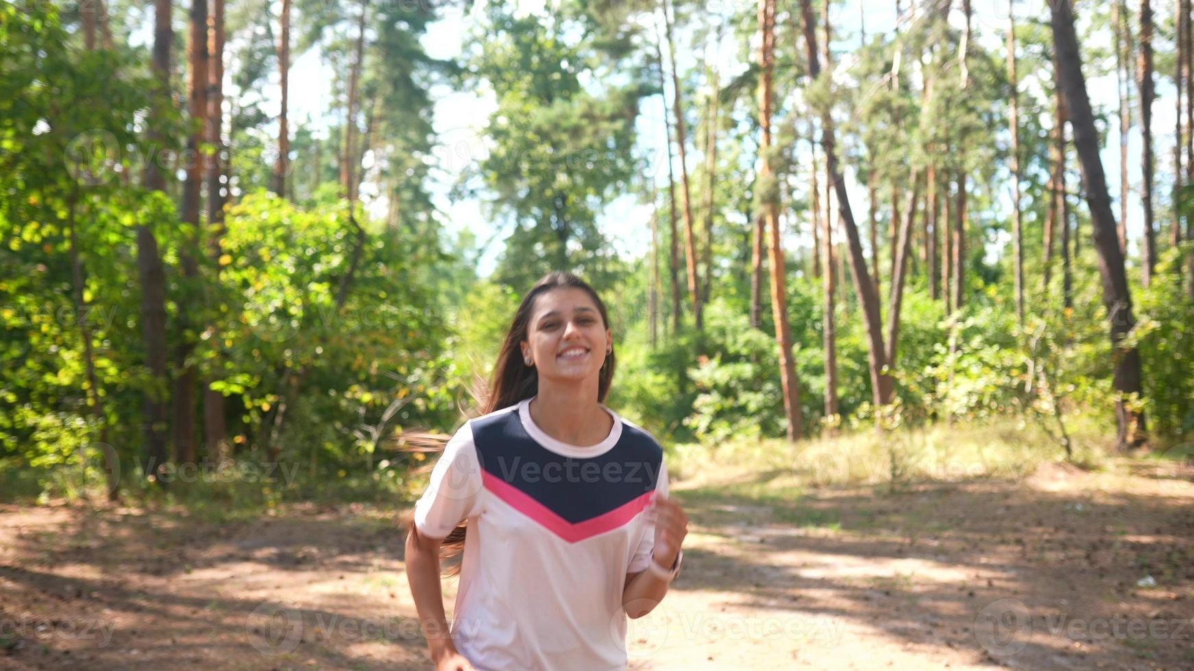 A young woman runs through a forest in slow motion. Front view. photo