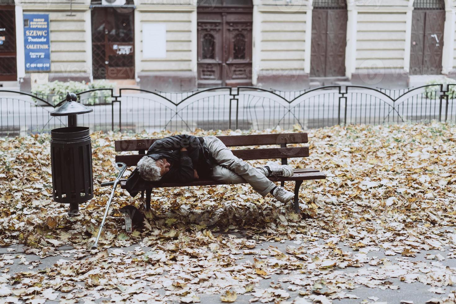 personas sin hogar durmiendo en los bancos en el parque de otoño foto