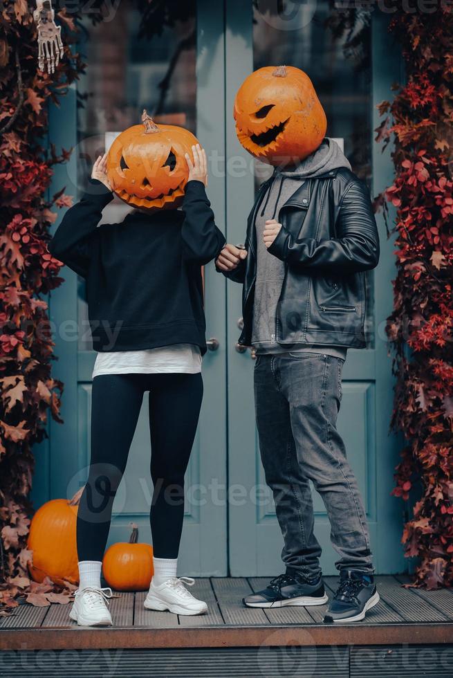Couple with pumpkin heads posing on camu at the building photo