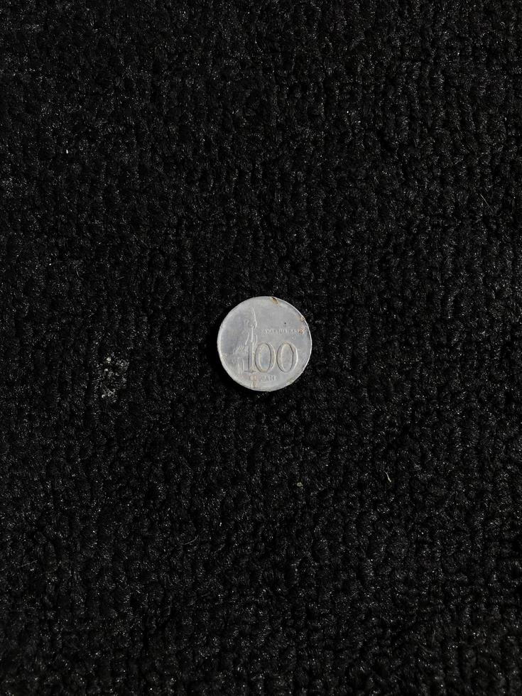 One hundred rupiah Indonesian coin with a picture of a parrot isolated on a dark background photo