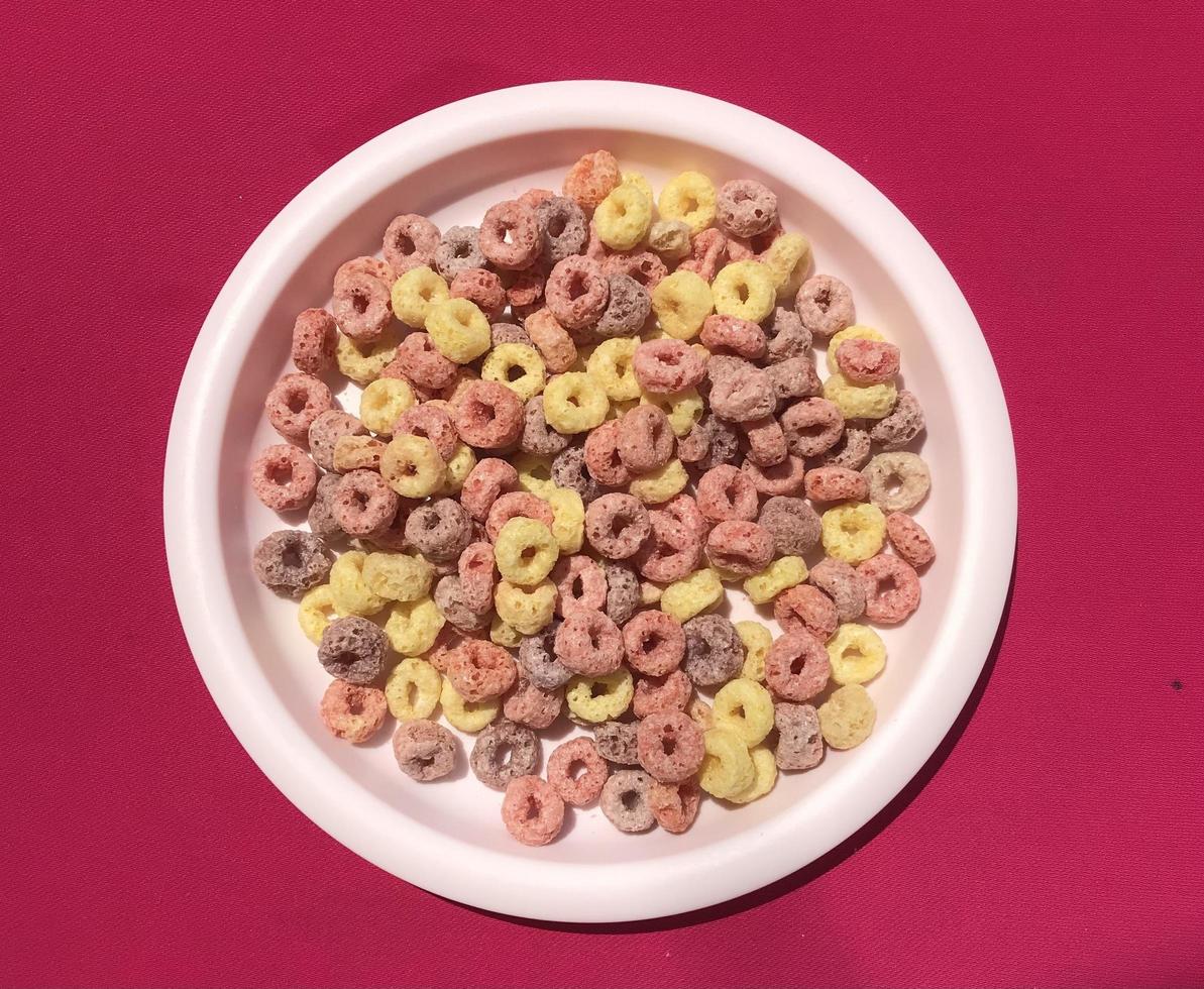Colorful cereal consisting of yellow, red and purple on a pink background photo