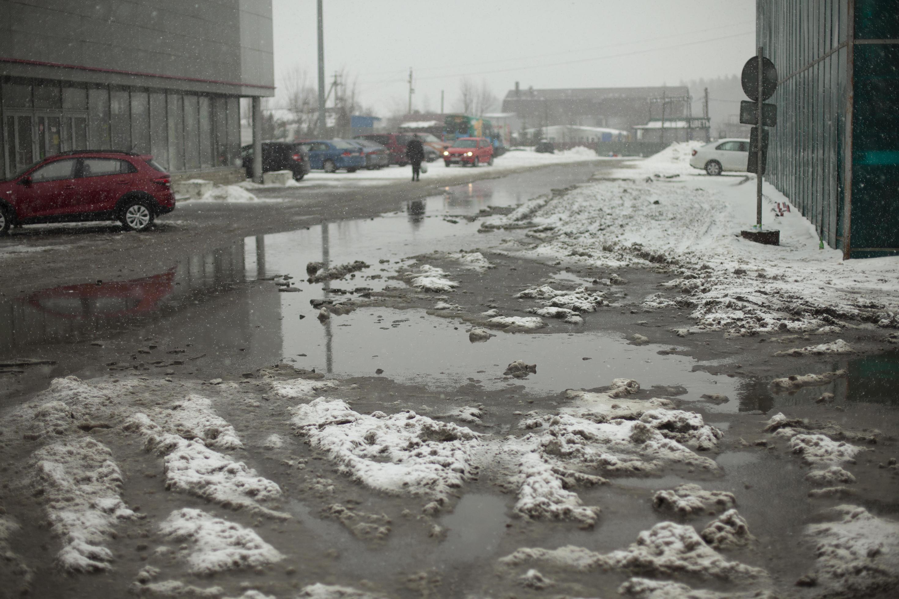Muddy puddle of melted snow on road. Uncleaned parking. 11732432 Stock
