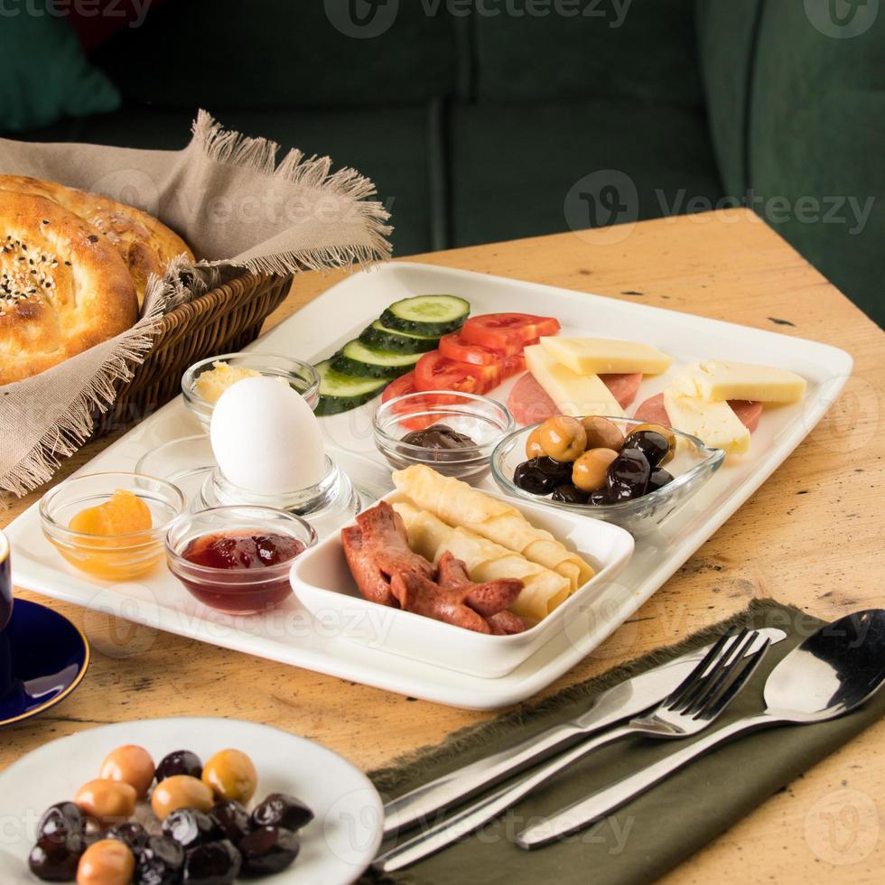 A breakfast plate and a basket of bread on a wooden table photo