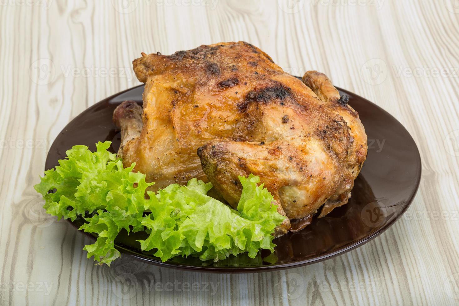 pollo asado en el plato y fondo de madera foto