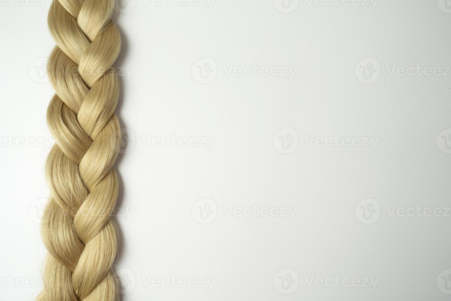 A strand of blonde hair lying on a white background photo