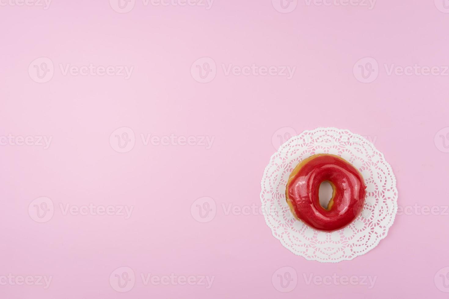 A tasty glazed donut lies on a pink background photo