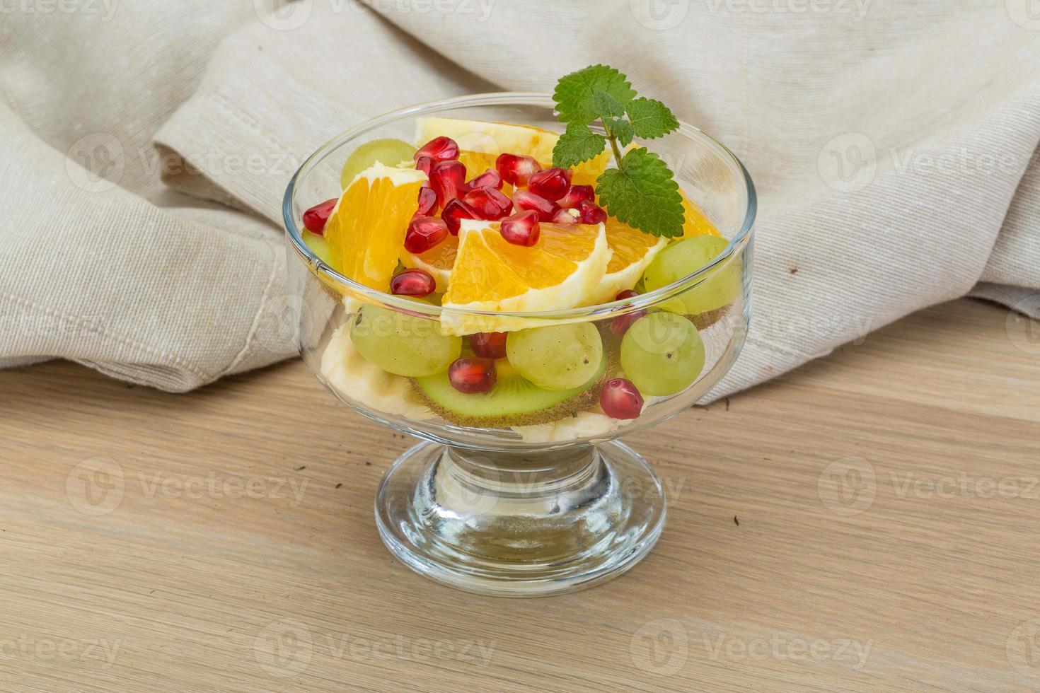 Fruit salad in a bowl on wooden background photo