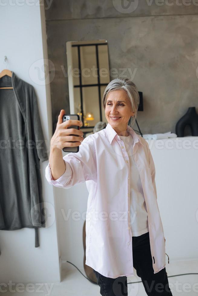 Cheerful confident excited dreamy elderly female taking selfie photo