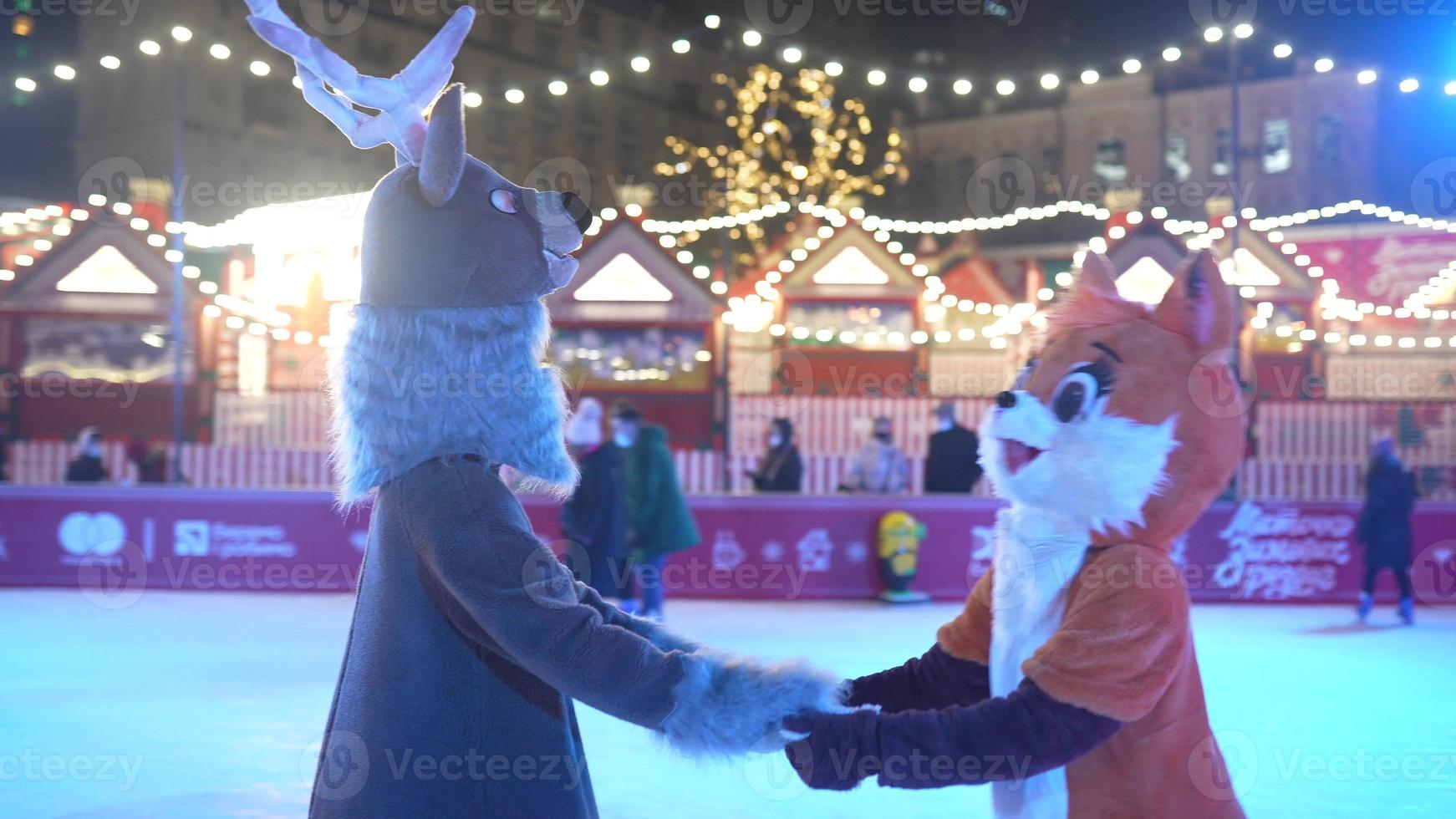 la gente disfruta del patinaje sobre hielo en la calle alrededor del árbol de navidad en la pista. foto