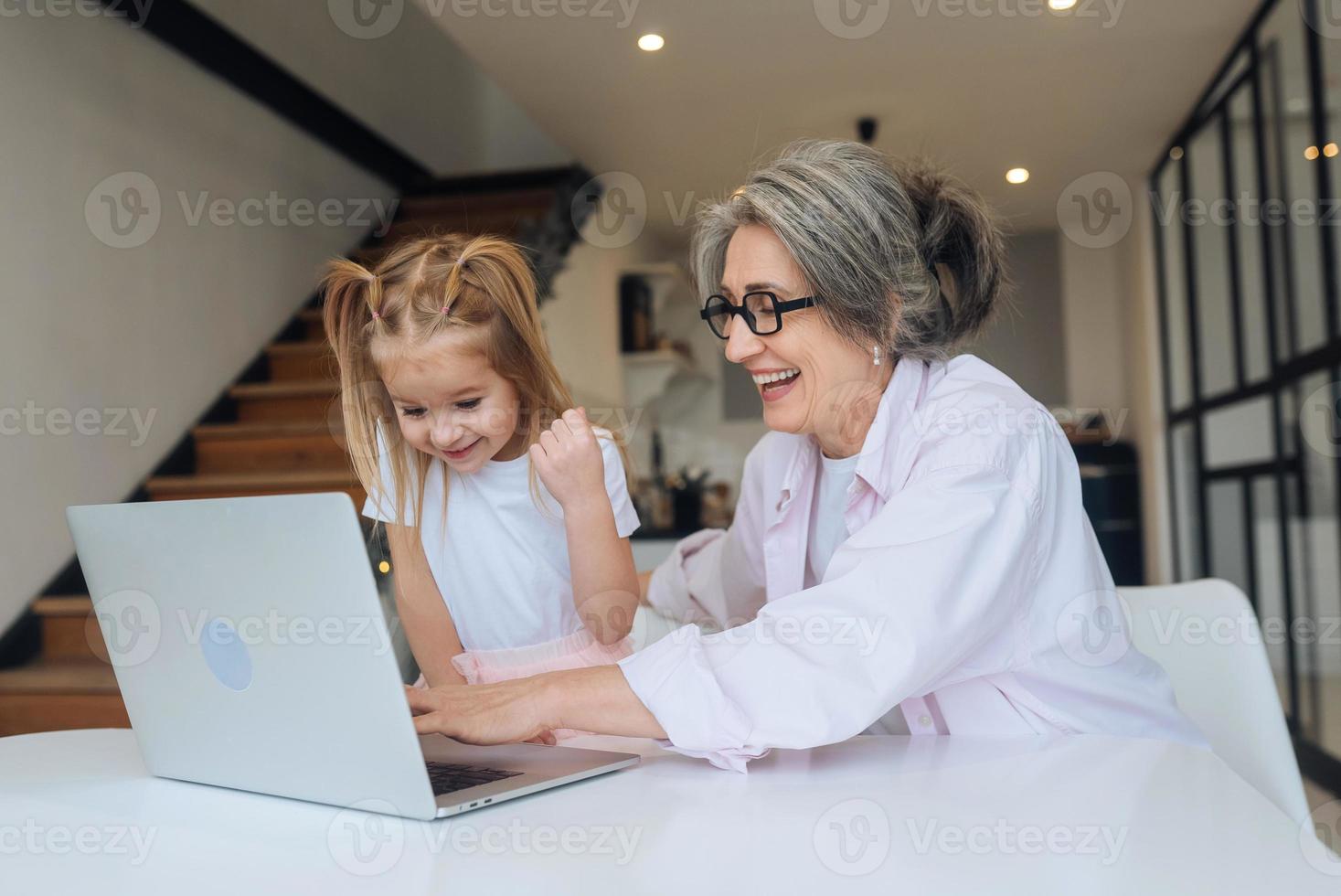 niño y abuela mirando la cámara con laptop foto