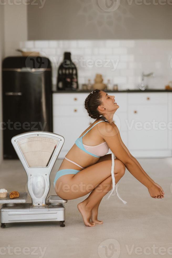 Woman in lingerie posing at the old grocery scales. Healthy eating concept photo