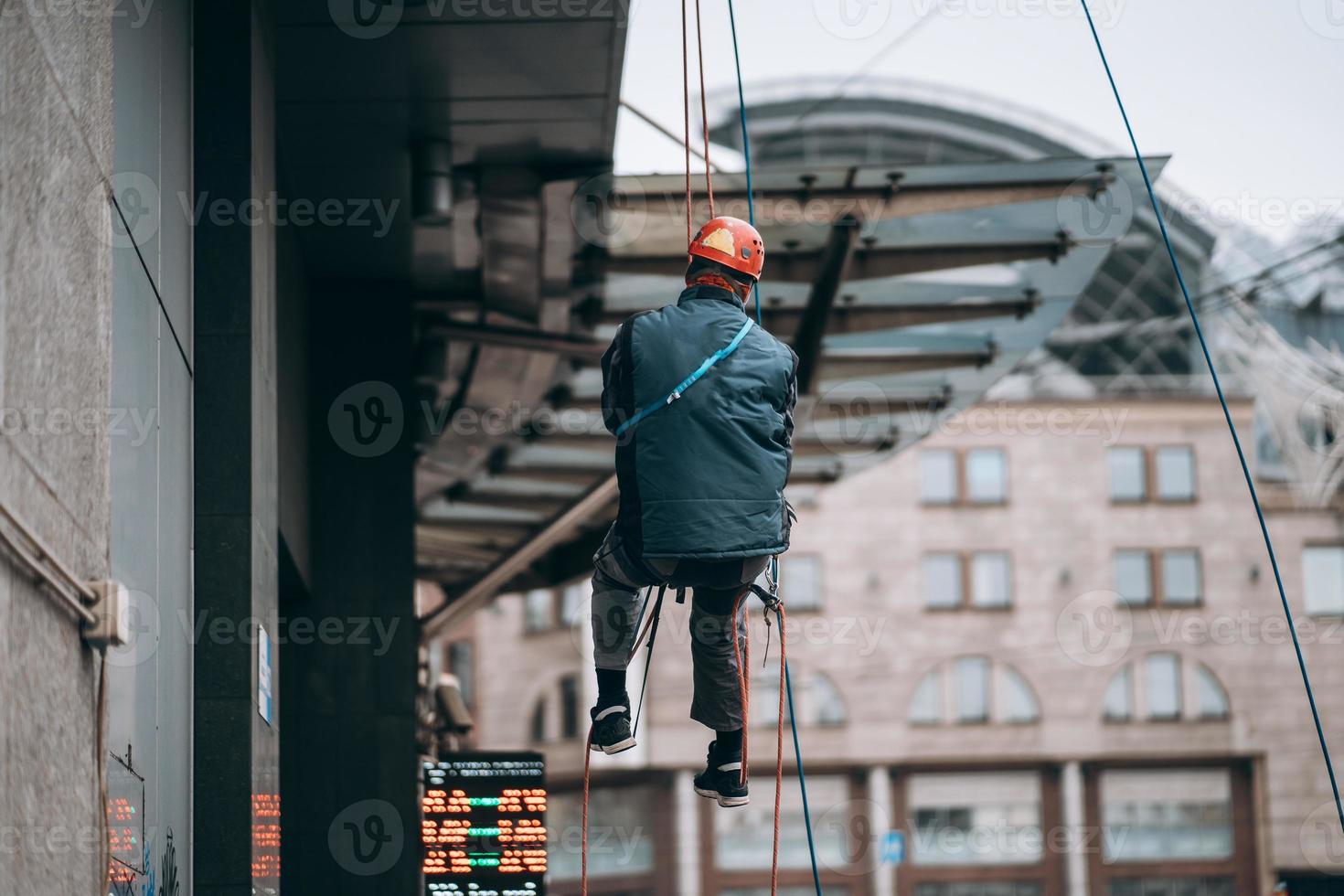 Industrial climber in uniform and helmet rises photo