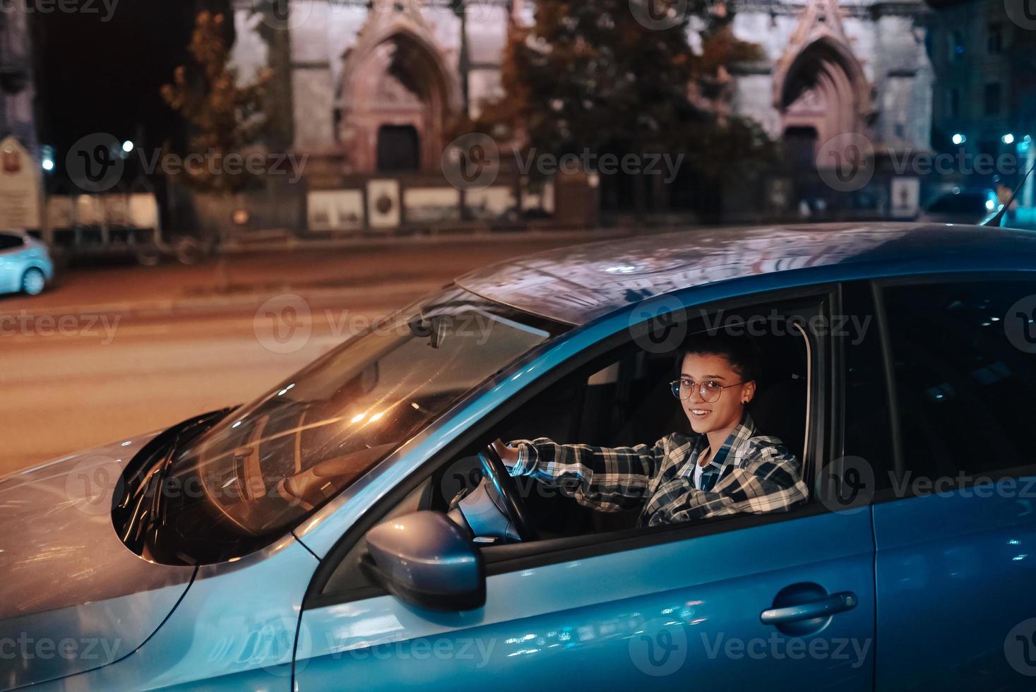 mujer conduciendo un coche por la noche en la ciudad foto