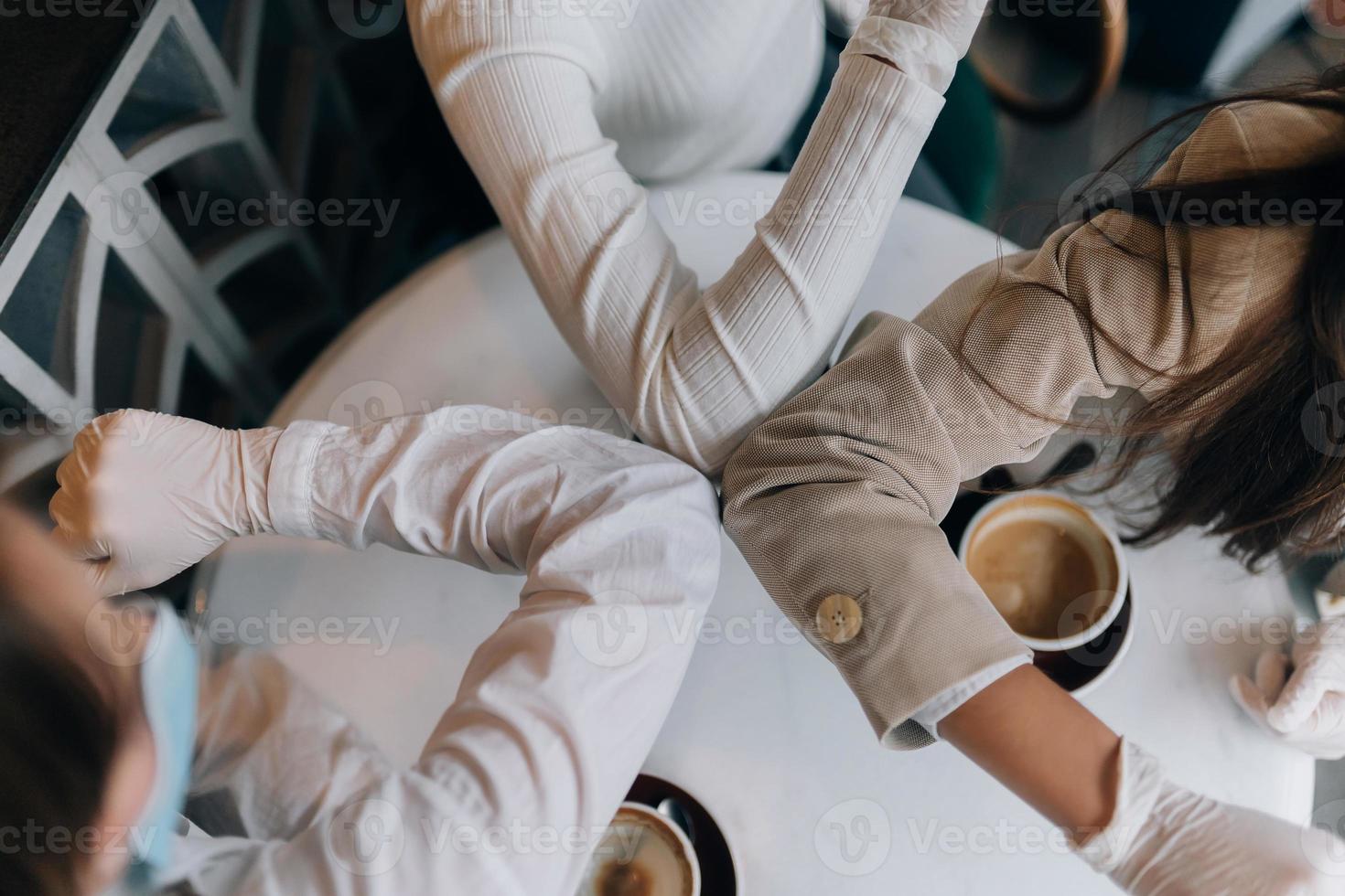 compañeros de trabajo con máscaras protectoras chocando los cinco con los codos. foto