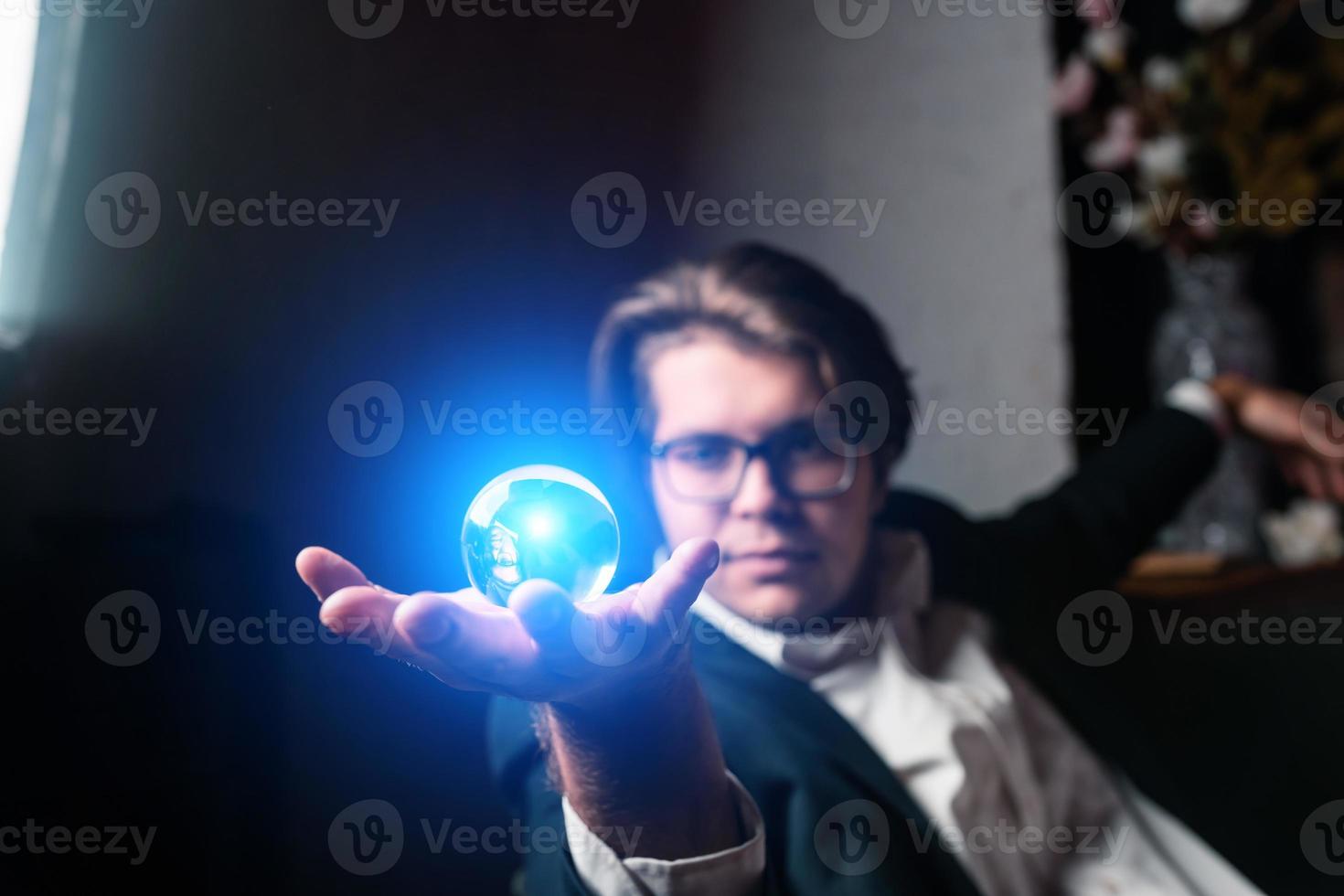 Young man holding a clear transparent crystal glass ball in their hand photo