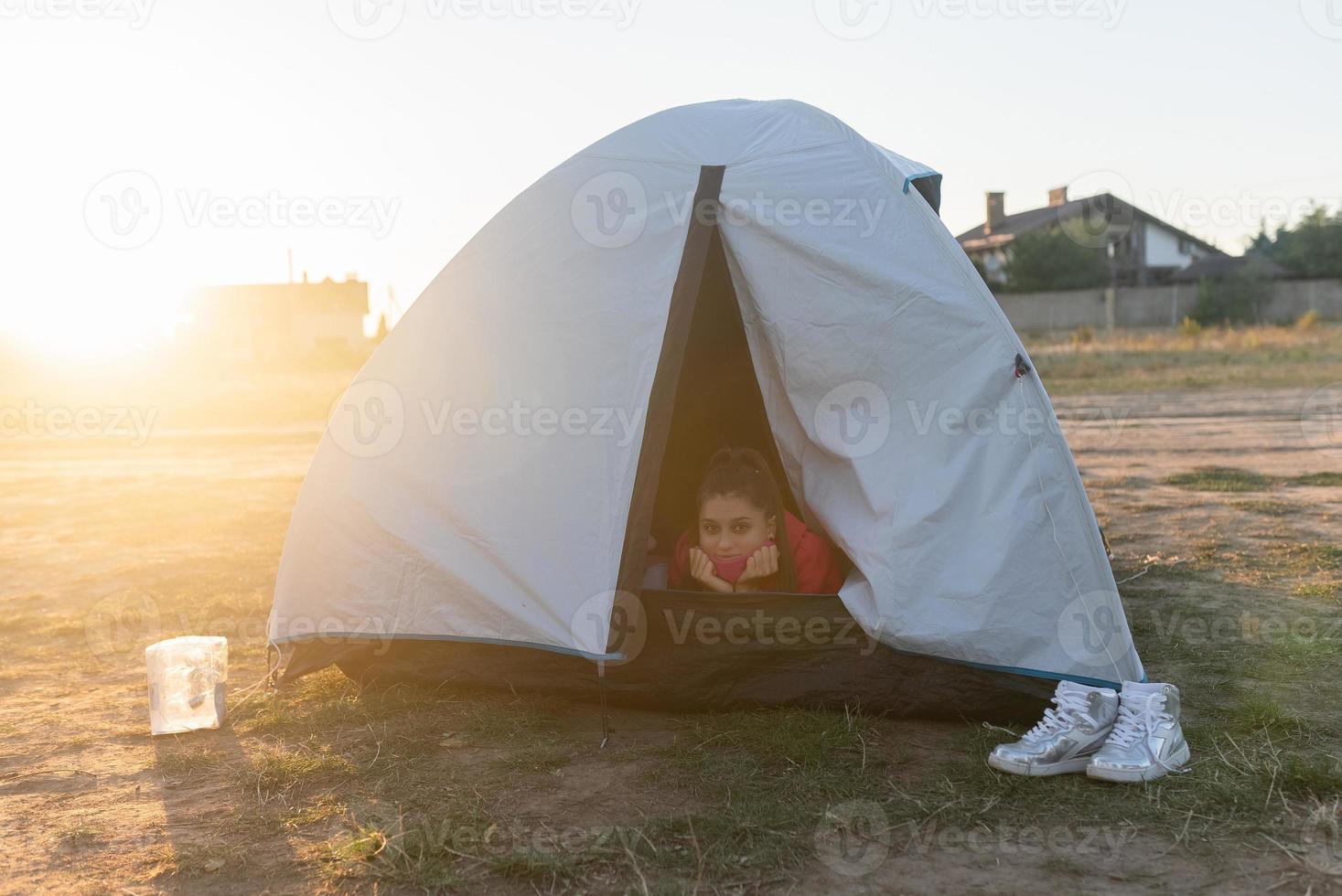 Young woman peeking out of the tent with only her head sticking out photo