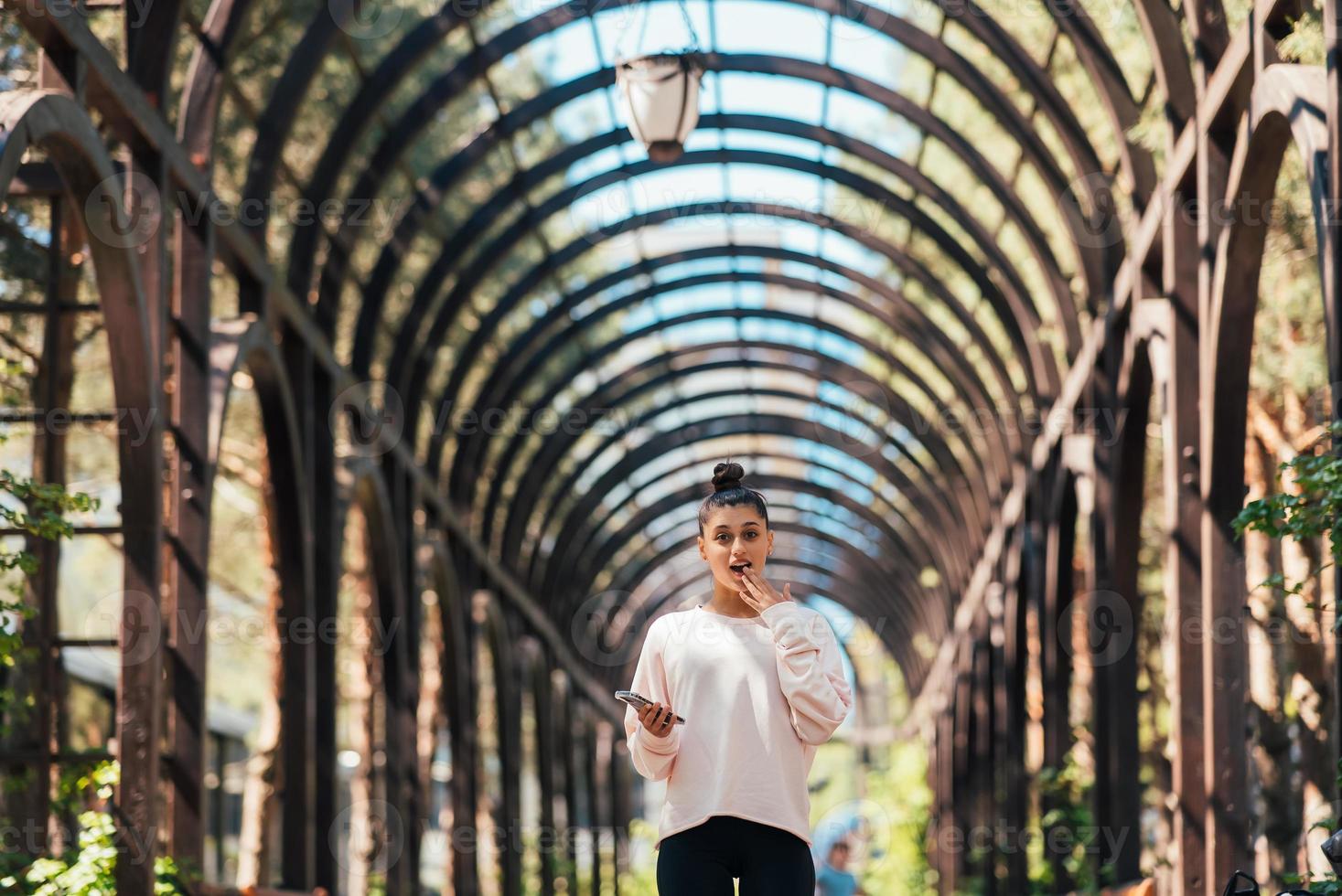 Beautiful young woman walks along a picturesque alley in summer park. photo