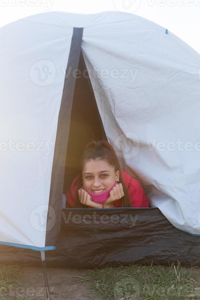 Young woman peeking out of the tent with only her head sticking out photo