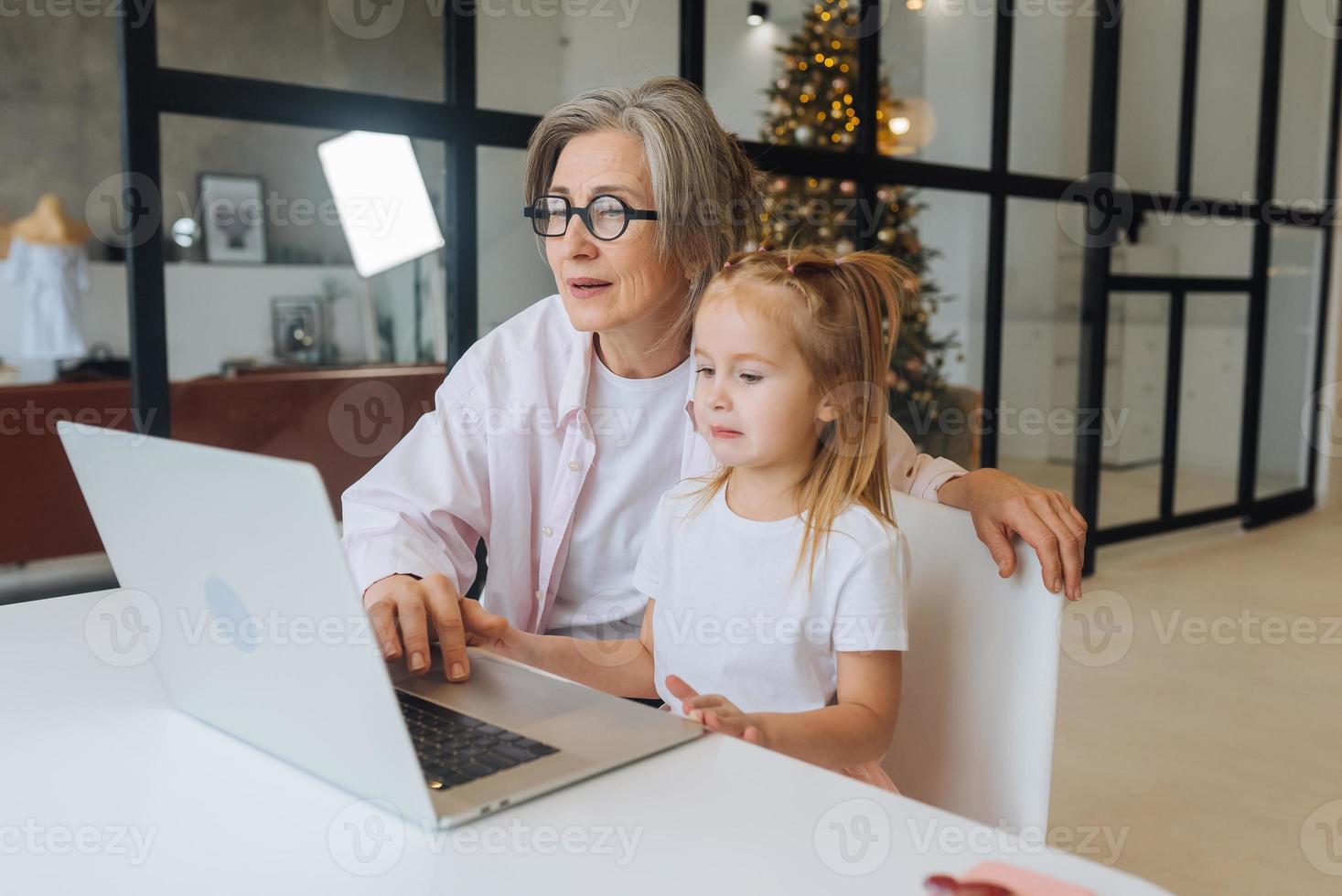 Child and granny looking at the camera with laptop photo